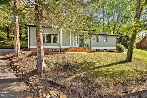 a front view of a house with a yard and large tree