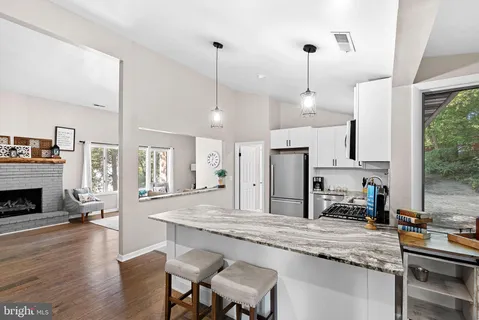 a kitchen with kitchen island granite countertop a stove a sink a dining table and chairs