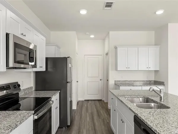 a kitchen with stainless steel appliances granite countertop a sink stove microwave and refrigerator