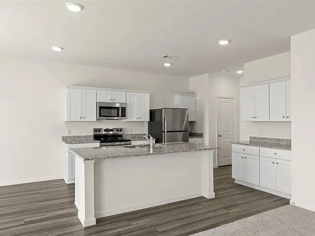 a kitchen with stainless steel appliances a sink a stove a microwave and cabinets