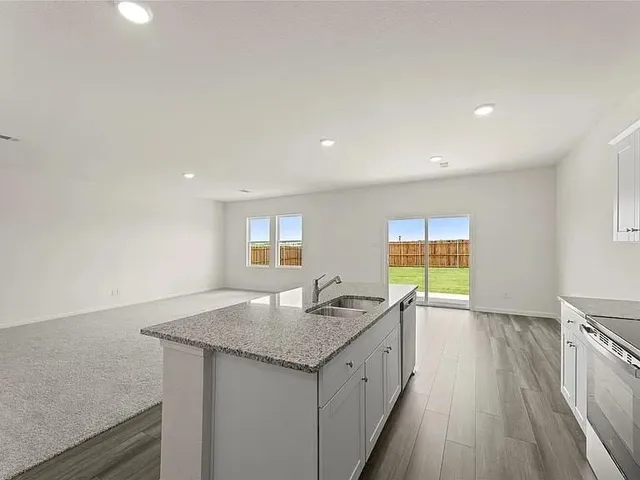 a kitchen with granite countertop sink cabinets and wooden floor