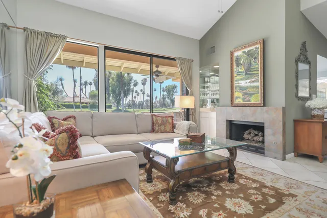 a living room with furniture a fireplace and large windows