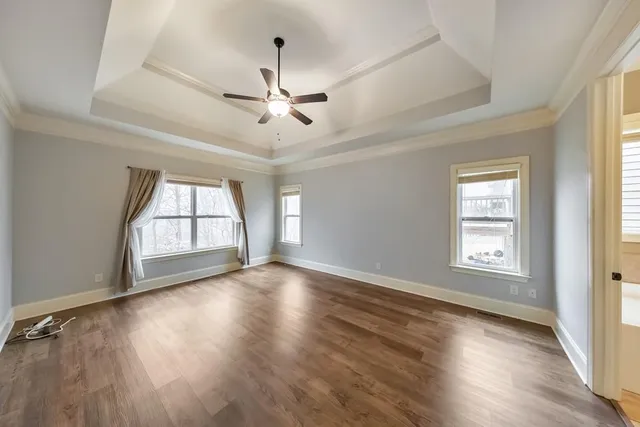 a view of empty room with wooden floor and fan