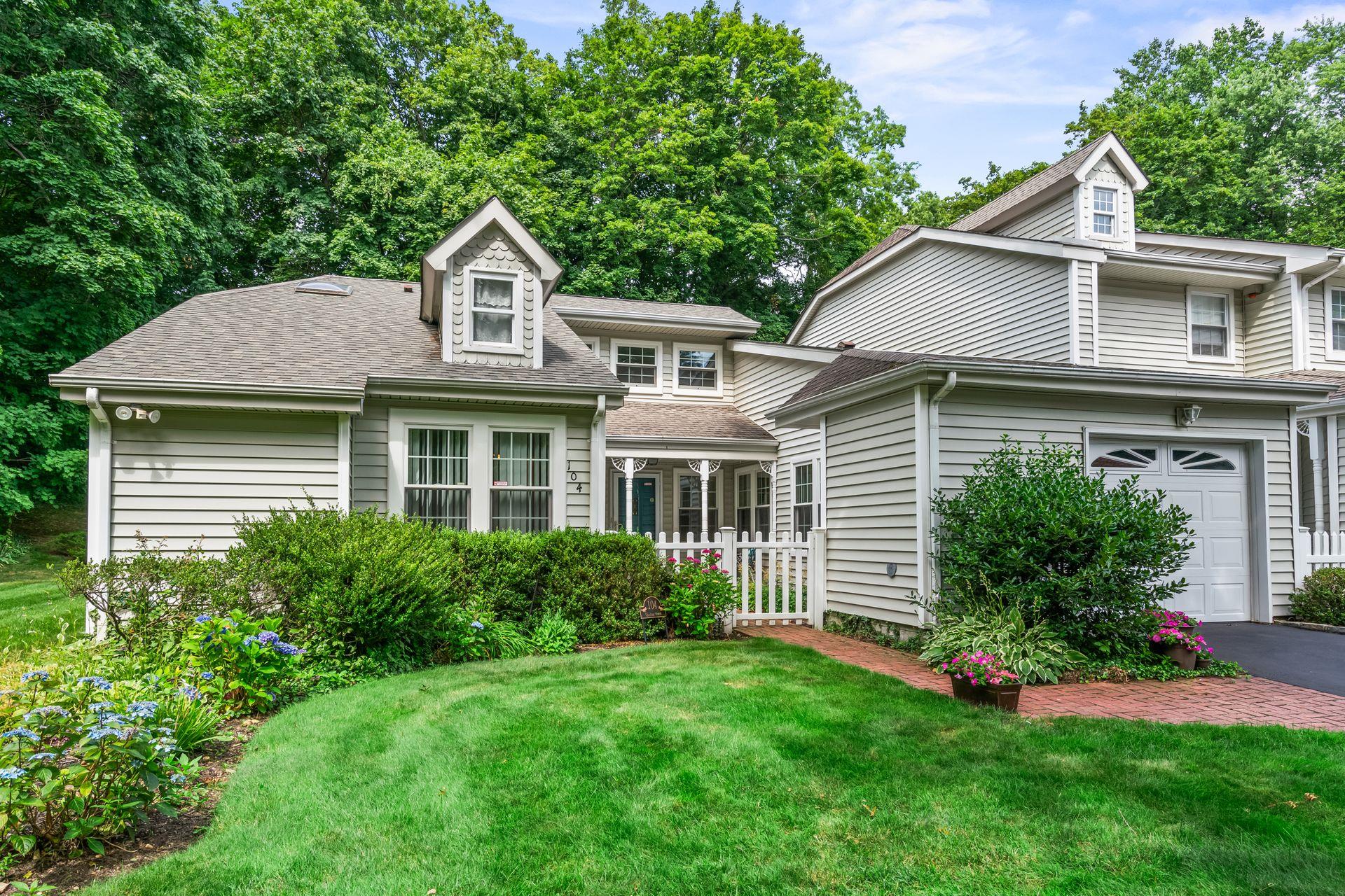 View of front of property featuring a front yard, asphalt driveway, roof with shingles, and an attached garage