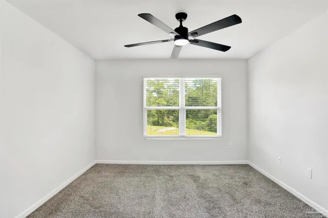 an empty room with ceiling fan and windows