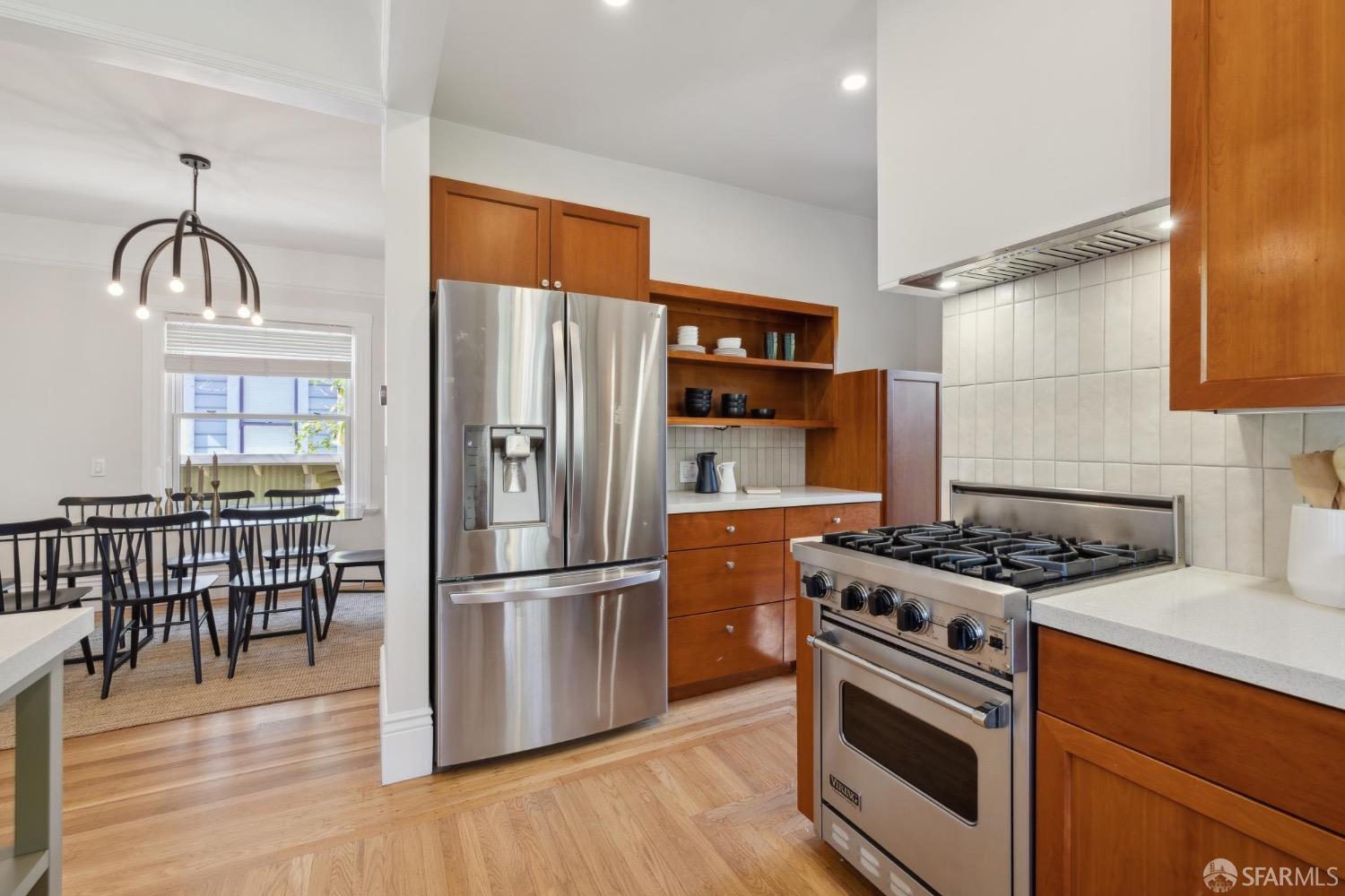 2341 Carleton Street Berkeley, CA 94704 - Photo 16 of 66 a kitchen with stainless steel appliances granite countertop a stove a refrigerator and a dining table with wooden floor