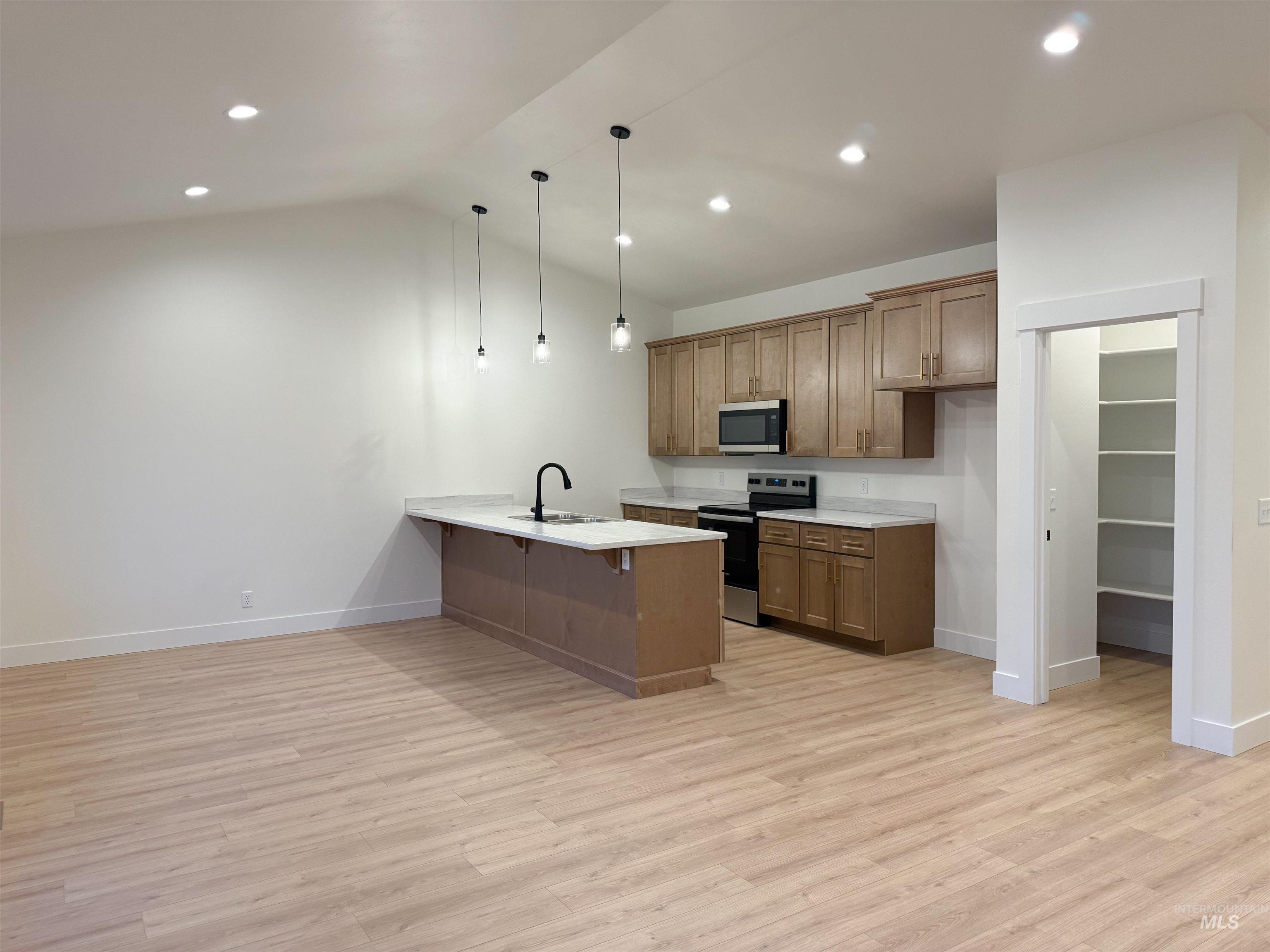 245 Whitman Street Albion, ID 83311 - Photo 3 of 15 Kitchen featuring a breakfast bar area, wood finish cabinetry, stainless steel appliances, a peninsula, and pendant lighting