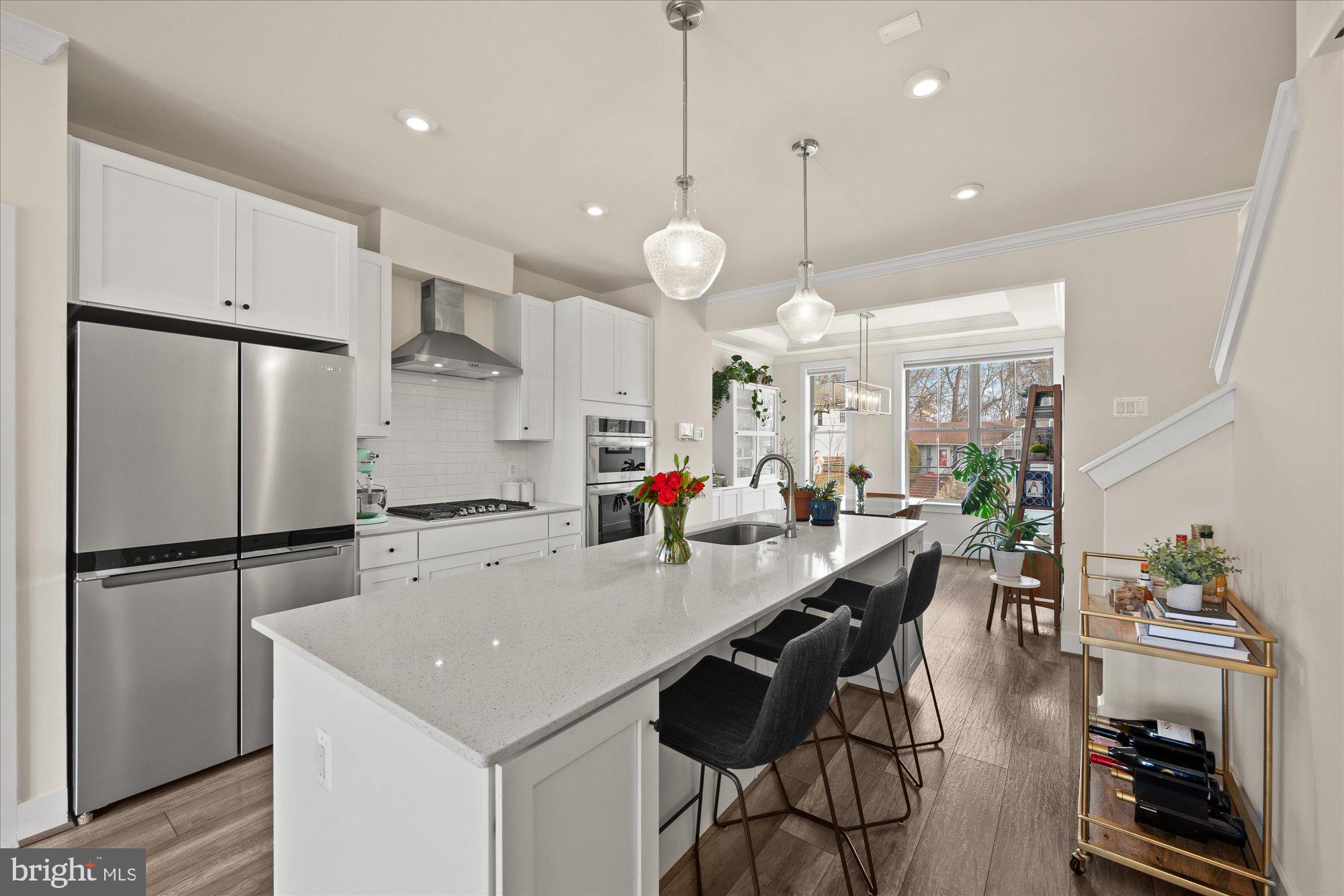 2236 South Glebe Road Arlington, VA 22206 - Photo 5 of 19 a kitchen with stainless steel appliances a stove a refrigerator a sink a dining table and chairs with wooden floor