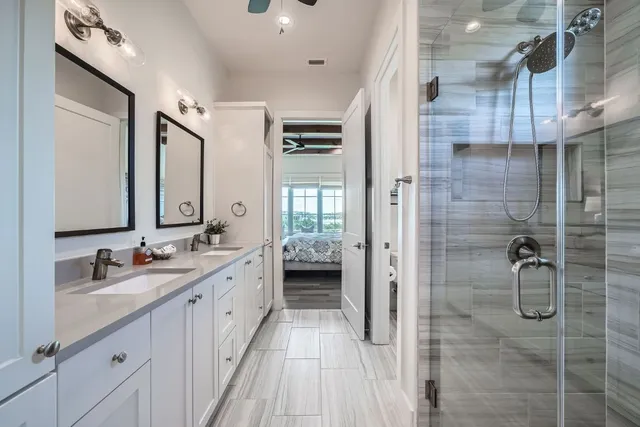 a spacious bathroom with a double vanity sink a mirror and shower