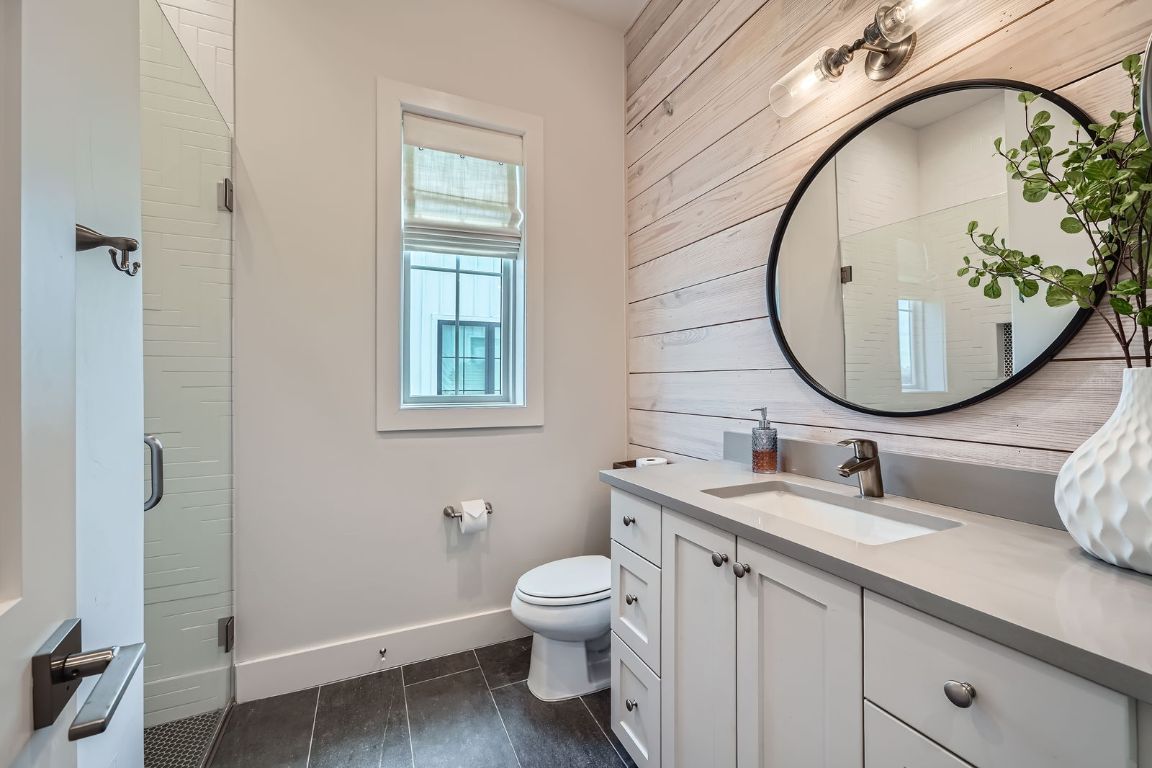 19517 Flying J Boulevard, Unit 8 Spicewood, TX 78669 - Photo 21 of 29 a bathroom with a toilet a sink and mirror