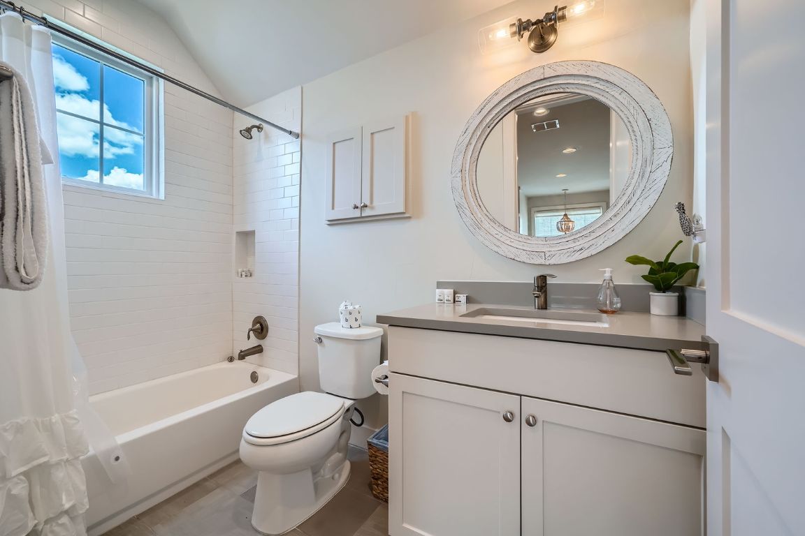 19517 Flying J Boulevard, Unit 8 Spicewood, TX 78669 - Photo 24 of 29 a bathroom with a toilet a sink a mirror a bathtub and vanity
