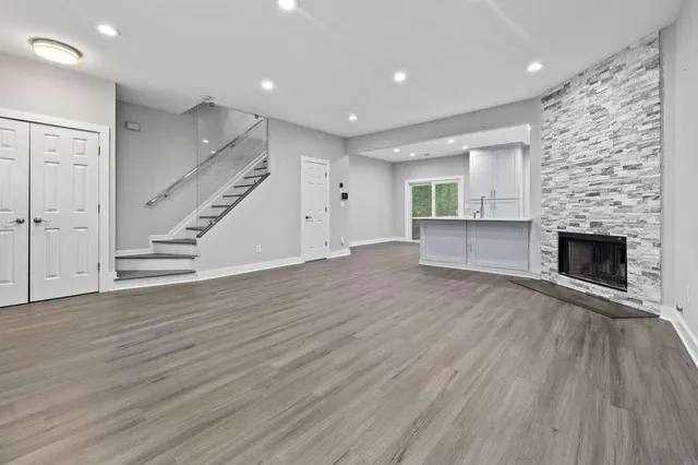 an empty room with wooden floor fireplace and windows