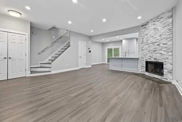 an empty room with wooden floor fireplace and windows