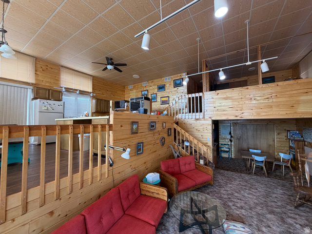 358 South Sky Drive Torrey, UT 84775 - Photo 14 of 82 Open-concept living area featuring extensive wood paneling, a mezzanine level, track lighting, a ceiling fan, and a kitchen with wood-finish cabinetry