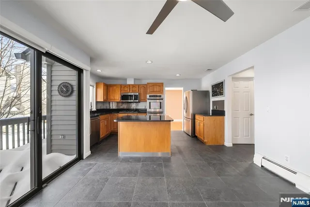 a kitchen with stainless steel appliances kitchen island granite countertop a refrigerator and a stove top oven