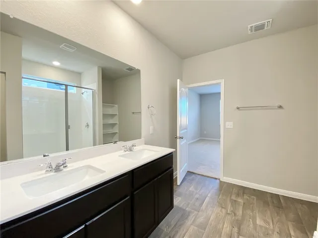 a bathroom with a double vanity sink a mirror and a shower