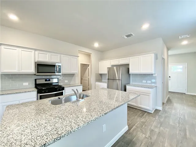 a large kitchen with granite countertop a large counter top stainless steel appliances and cabinets