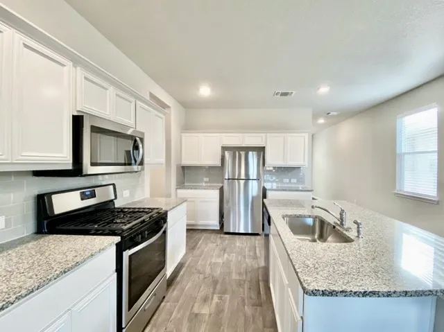 a kitchen with stainless steel appliances granite countertop a sink stove and refrigerator