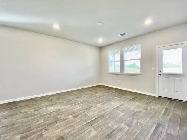 an empty room with wooden floor and windows