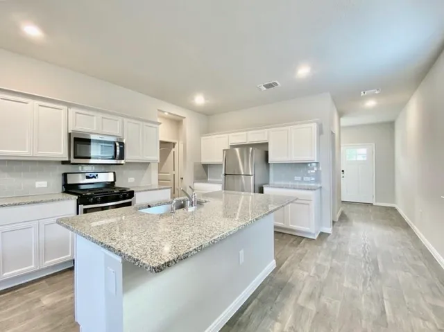 a kitchen with stainless steel appliances granite countertop a sink dishwasher stove and refrigerator