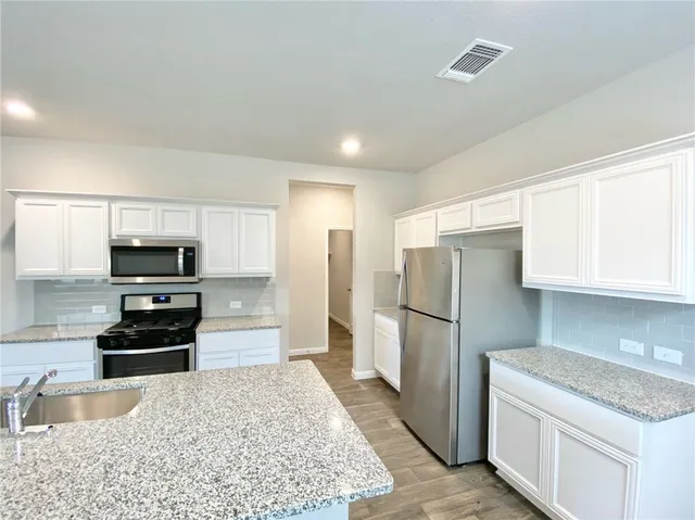 a kitchen with granite countertop a refrigerator and a sink
