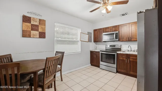 a kitchen with stainless steel appliances kitchen island granite countertop a stove top oven a sink a dining table and chairs