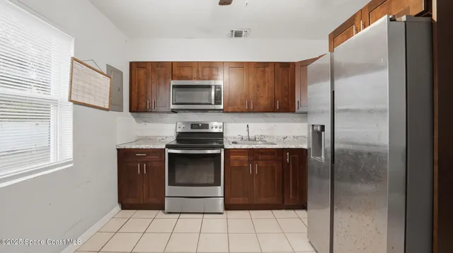 a kitchen with granite countertop a refrigerator and a stove top oven