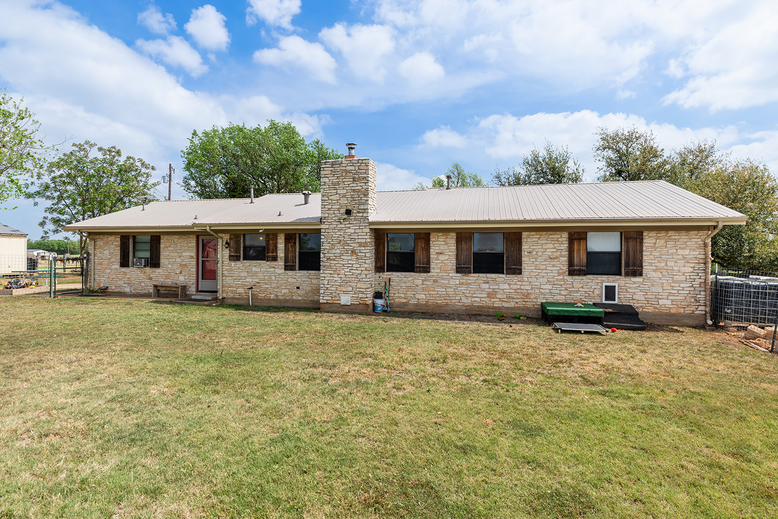 1001 Gravel Pit Road Taylor, TX 76574 - Photo 20 of 38 Rear view of house with stone siding, a chimney, and a metal roof