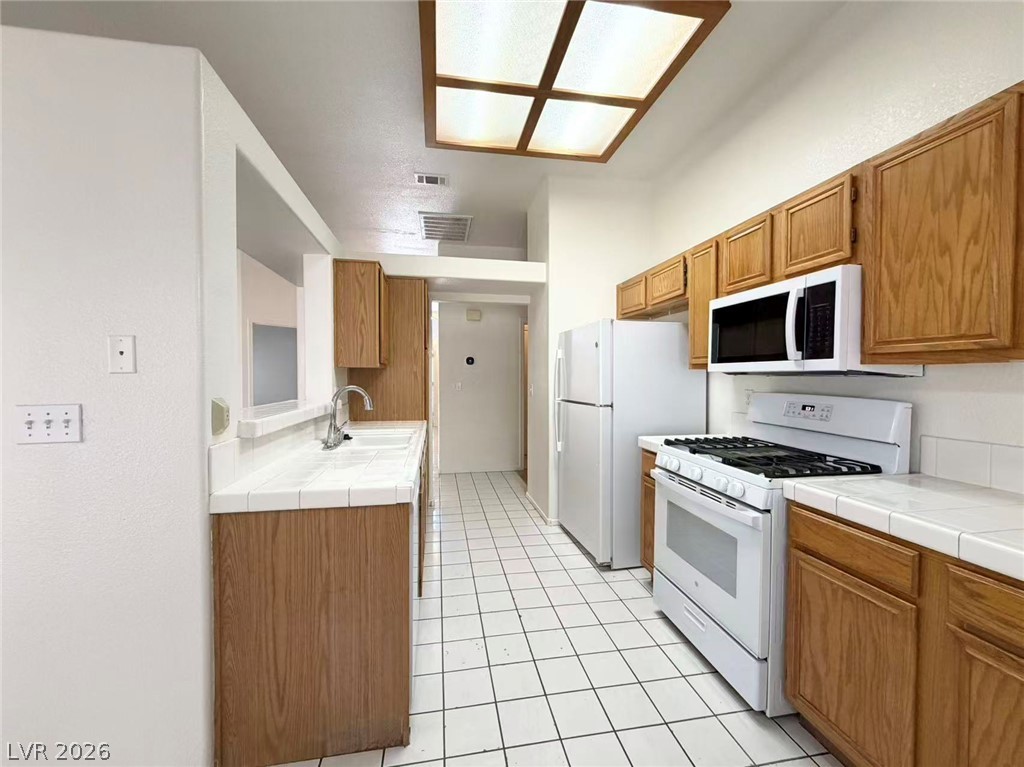 8620 Magnolia Ridge Avenue Las Vegas, NV 89134 - Photo 4 of 15 A well-equipped kitchen features wooden cabinetry and bright tile flooring, ready for culinary endeavors.
