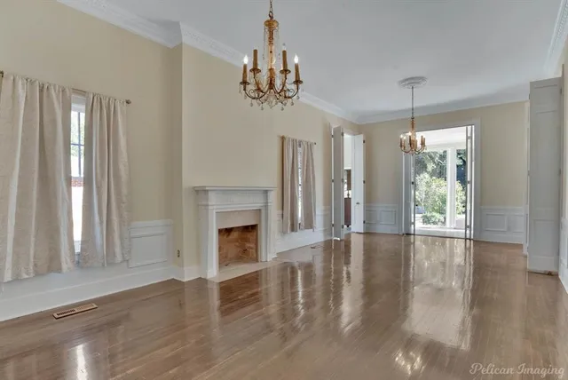 a view of an empty room with wooden floor fireplace and a window