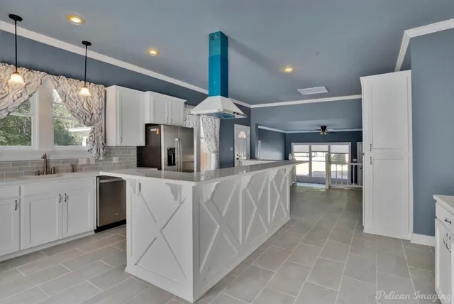 a kitchen with stainless steel appliances kitchen island granite countertop a refrigerator a sink dishwasher and white cabinets with wooden floor