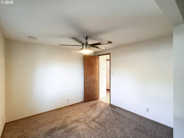 an empty room with a ceiling fan and a window