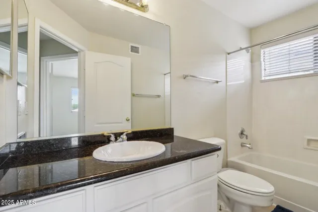 a bathroom with a granite countertop sink a toilet a mirror and shower