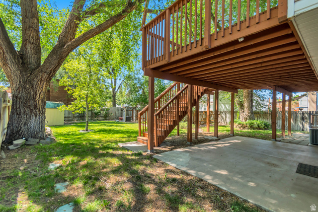 7652 South 520 East Midvale, UT 84047 - Photo 32 of 36 Expansive backyard featuring a large mature tree, manicured lawn, and a multi-level wooden deck with staircase access