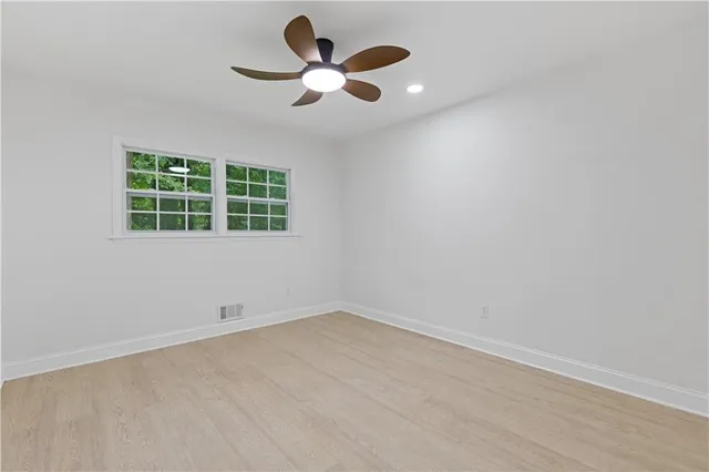 an empty room with a window and a fan