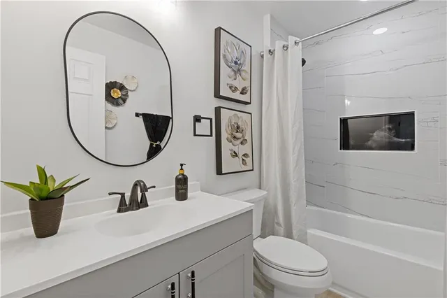 a bathroom with a toilet a sink a mirror a bathtub and shower