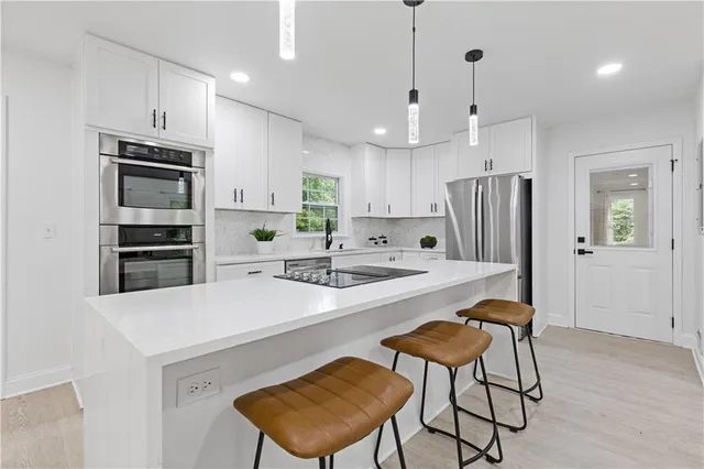 a kitchen with stainless steel appliances kitchen island a table chairs refrigerator and microwave