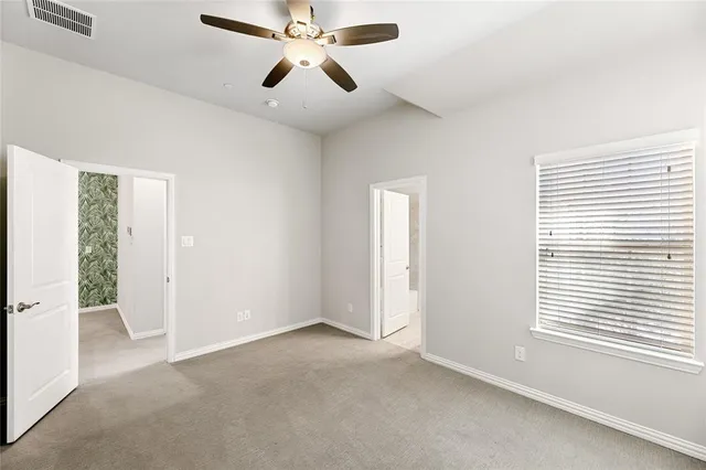 an empty room with windows and fan