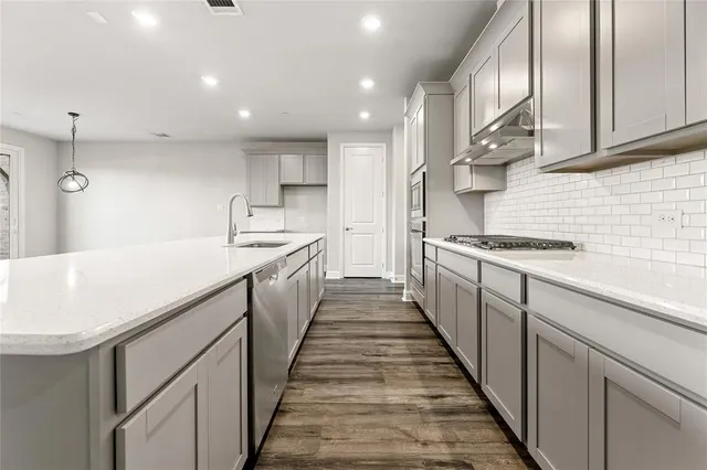 a kitchen with kitchen island granite countertop lots of counter top space and stainless steel appliances