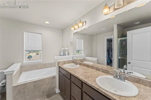 a bathroom with a granite countertop tub sink and mirror