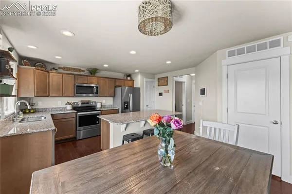 a kitchen with granite countertop kitchen island stainless steel appliances a sink and a refrigerator