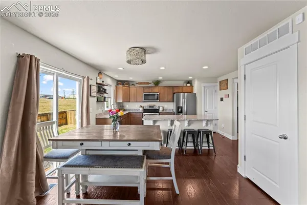a kitchen with a dining table chairs and refrigerator