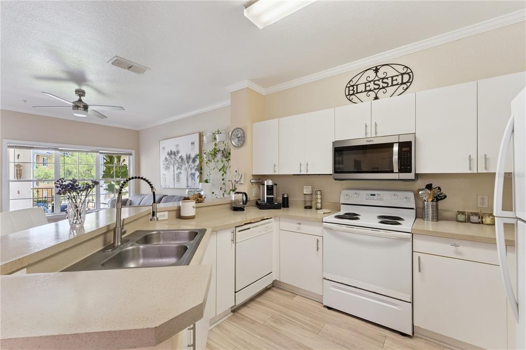 3751 Conroy Road, Unit 2325 Orlando, FL 32839 - Photo 10 of 31 a kitchen with white cabinets a sink a stove a oven with a dining table and chairs