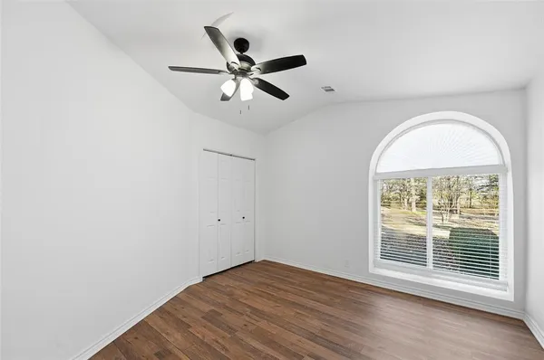 an empty room with wooden floor closet and fan