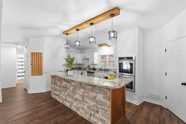 a kitchen with stainless steel appliances granite countertop a sink dishwasher stove and refrigerator with wooden floor