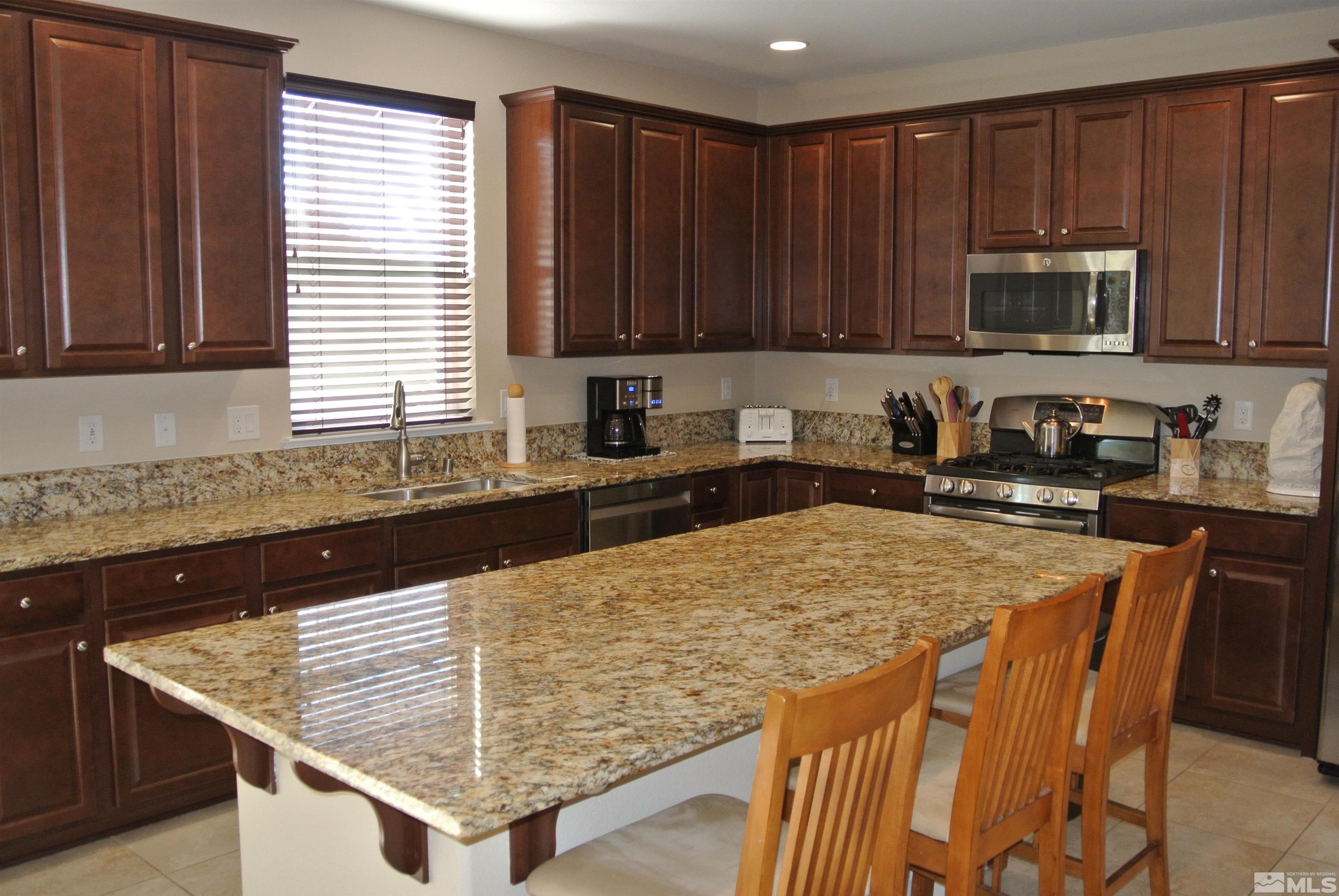 1888 Cholula Drive Reno, NV 89521 - Photo 2 of 17 a kitchen with stainless steel appliances kitchen island granite countertop a sink table and chairs