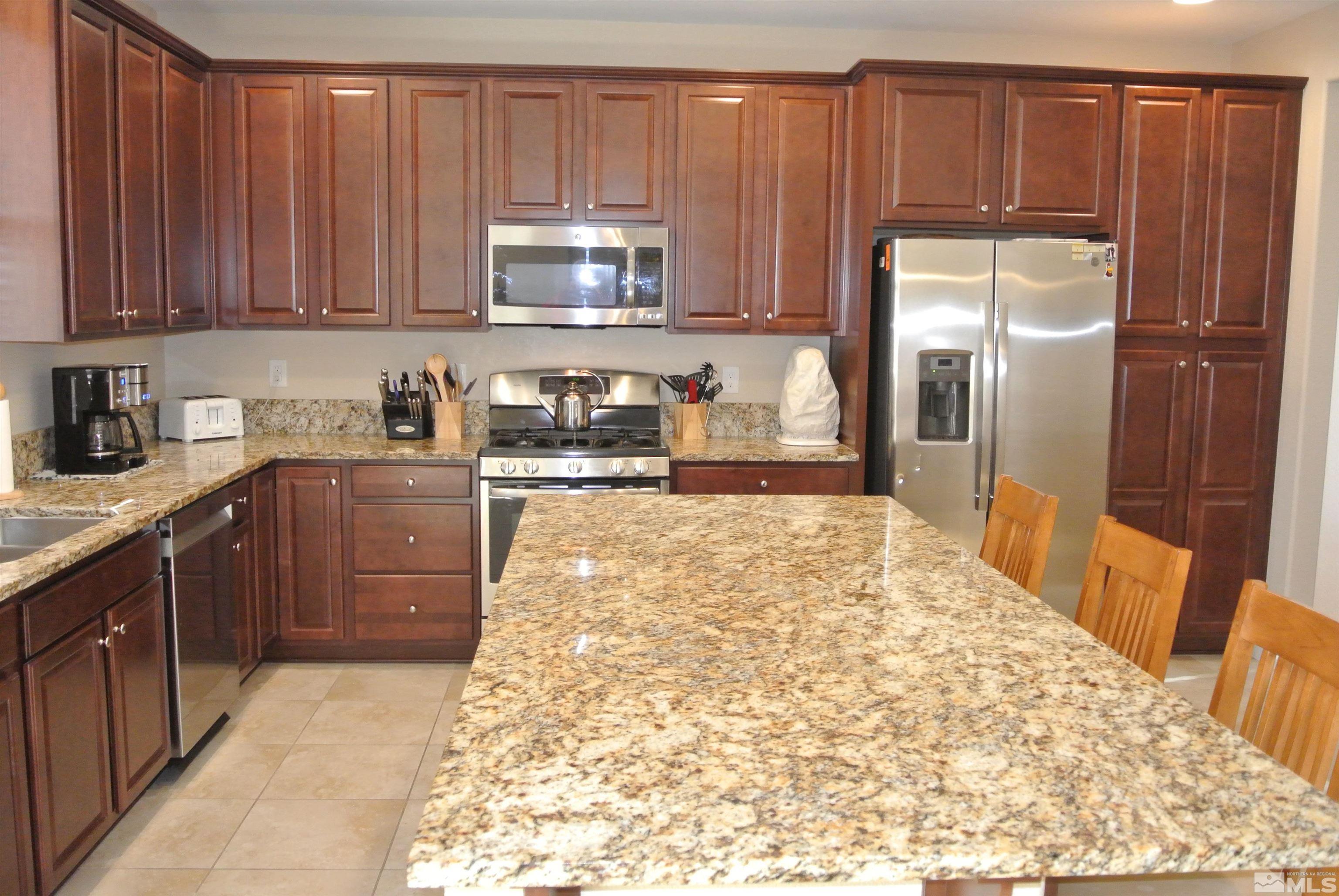 1888 Cholula Drive Reno, NV 89521 - Photo 3 of 17 a kitchen with stainless steel appliances a refrigerator sink and cabinets
