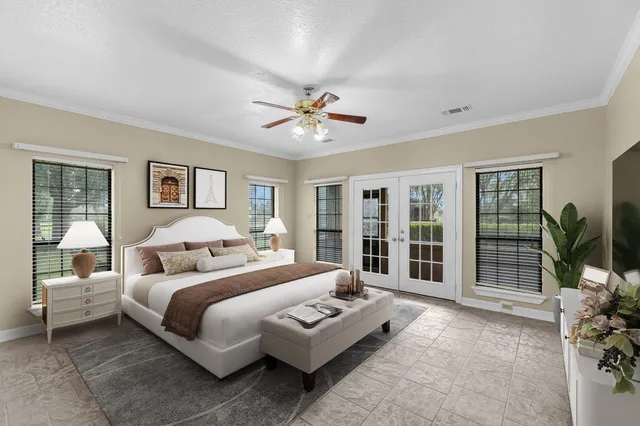 a bedroom with a large bed and a chandelier fan