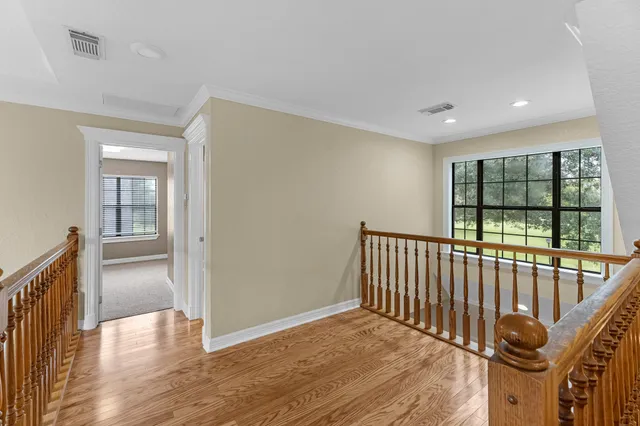 a view of a hallway with wooden floor and windows