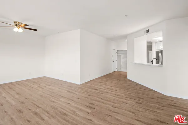 a view of empty room with wooden floor and fan